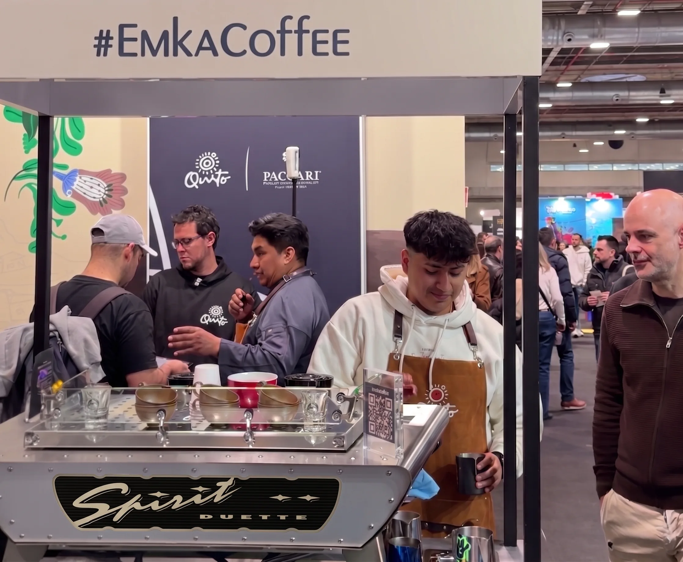 Barista de EMKA Coffee atendiendo a clientes en un stand de feria
